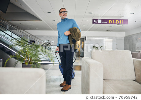 Joyous man standing at the airport terminal Joyous man standing at the airport terminal 70959742