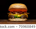 Close up fresh tasty the hamburger with cheese, tomato, beef, bacon and green salad vegetable, selective focusing technical, wooden table and darkness background. 70960849
