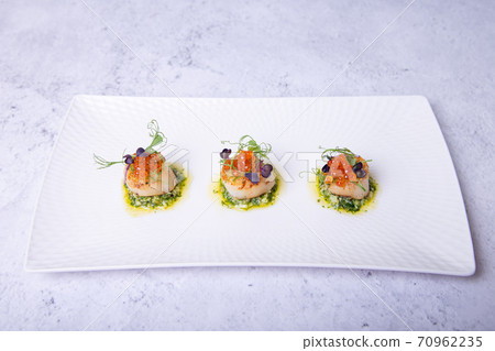 Scallops with caviar, microgreens and green sauce on a white plate. Close-up. 70962235