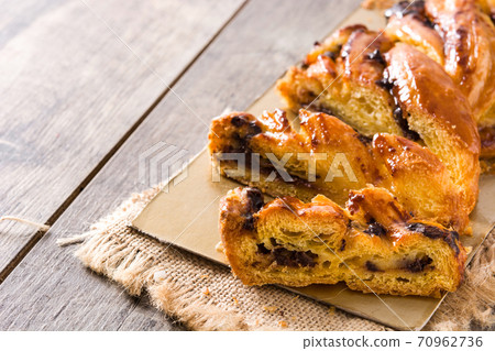 Homemade braid stuffed with chocolate and cut into pieces on wooden table. Flat lay top-down composition 70962736
