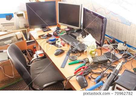 A messy desktop with stacks of files and other documents, all kind of office supplies and part of a keyboard. 70962782