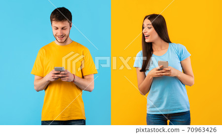 Happy lady and guy using mobile phone at studio 70963426