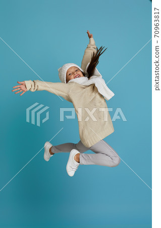 little child girl in winter knitted hat and sweater jumping 70963817