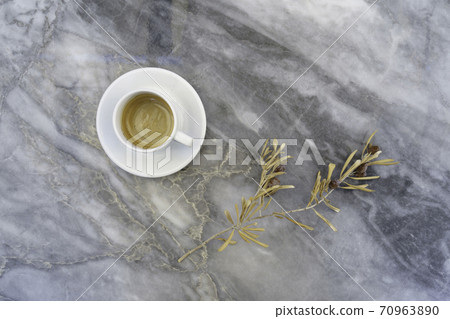 dry olive tree branch with olives, coffee cup on marble grey table  70963890
