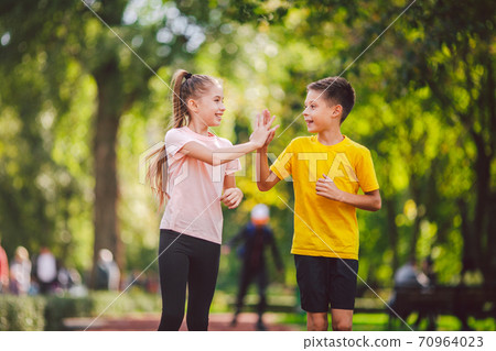 Sports and fitness in adolescence. Caucasian twins boy and girl run on the jogging track in the city park. Two children brother and sister for 10 years running on a rubberized outdoor treadmill Sports and fitness in adolescence. Caucasian twins boy and girl run on the jogging track in the city park. Two children brother and sister for 10 years running on a rubberized outdoor treadmill 70964023
