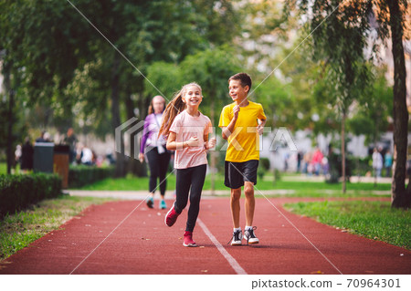 Child fitness, twins kids running on stadium track in city park , training and children sport healthy lifestyle. Outdoor activities by running make the child's body healthy and experience enriched Child fitness, twins kids running on stadium track in city park , training and children sport healthy lifestyle. Outdoor activities by running make the child's body healthy and experience enriched 70964301