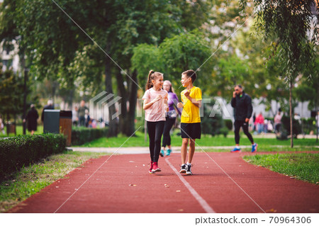 Child fitness, twins kids running on stadium track in city park , training and children sport healthy lifestyle. Outdoor activities by running make the child's body healthy and experience enriched 70964306