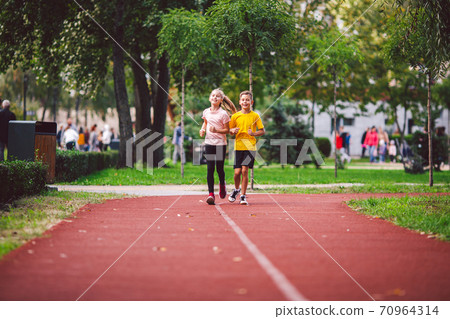 Kids run. Healthy sport. Child sport, heterosexual twins running on track, fitness. Joint training. Running training outdoor brother and sister pre-teen. Jogging with friend. Children athletes Kids run. Healthy sport. Child sport, heterosexual twins running on track, fitness. Joint training. Running training outdoor brother and sister pre-teen. Jogging with friend. Children athletes 70964314