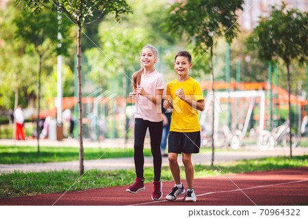 Child fitness, twins kids running on stadium track in city park , training and children sport healthy lifestyle. Outdoor activities by running make the child's body healthy and experience enriched 70964322