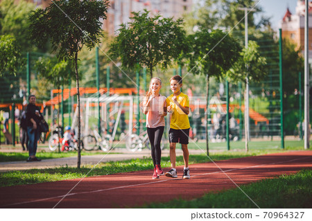 Child fitness, twins kids running on stadium track in city park , training and children sport healthy lifestyle. Outdoor activities by running make the child's body healthy and experience enriched 70964327