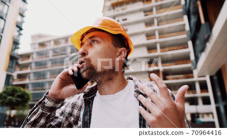 Engineer talking on phone. Architect using phone on construction site. Foreman phone call control process. Construction worker communications in construction industry. Building professional phone 70964416