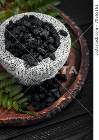 Close up of black raisins in a stone bowl, close up, dark background Close up of black raisins in a stone bowl, close up, dark background 70965161