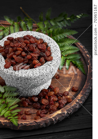 Close up of black raisins in a stone bowl, close up, dark background 70965167