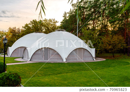 Summer-type cafe with cloth tent on the roof in the form of a dome with wooden entrance doors 70965823