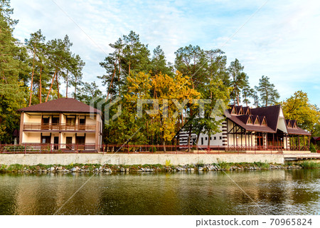 A small complex hotel in the forest consisting of several houses in pines on the banks of the river. A small complex hotel in the forest consisting of several houses in pines on the banks of the river. 70965824