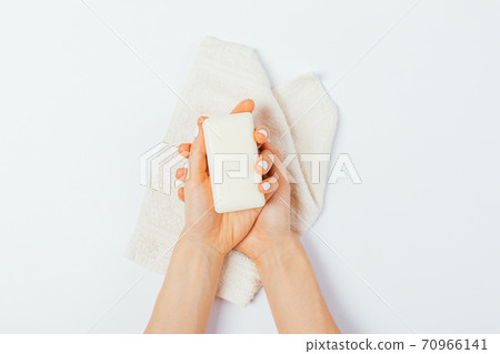 Female hands hold bar of soap above towel Female hands hold bar of soap above towel 70966141