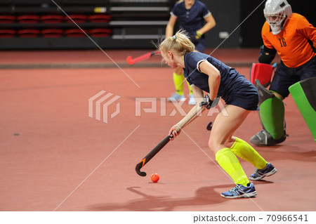Young woman player in attack at indoor hockey match Young woman player in attack at indoor hockey match 70966541