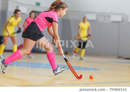 Young woman player in attack at indoor hockey match Young woman player in attack at indoor hockey match 70966542