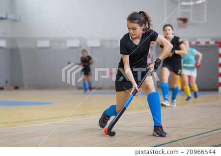 Young woman player in attack at indoor hockey match 70966544