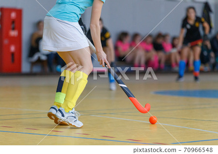 Young woman player in attack at indoor hockey match 70966548
