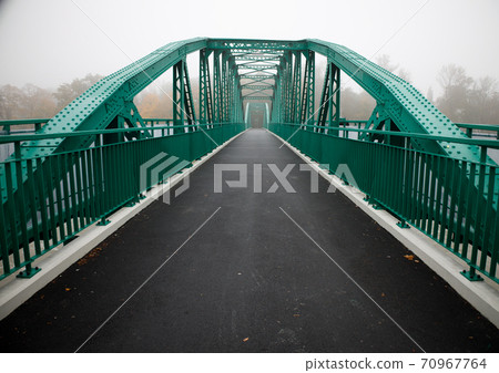 green bridge on an early foggy autumn morning on which no one walks. green bridge on an early foggy autumn morning on which no one walks. 70967764