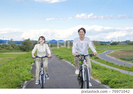 Men and women cycling Men and women cycling 70971042