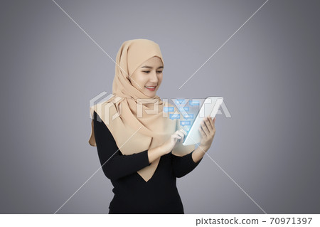 Happy muslim woman use tablet working over gray background. Happy muslim woman use tablet working over gray background. 70971397