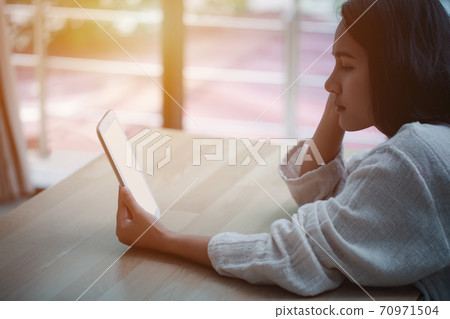 Young asian woman smiling and using tablet. Young asian woman smiling and using tablet. 70971504