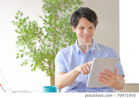 A businessman who taps a tablet with a smile A businessman who taps a tablet with a smile 70971950