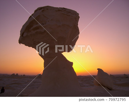 A mysterious rock silhouette of the Egyptian white desert where the setting sun sets 70972795