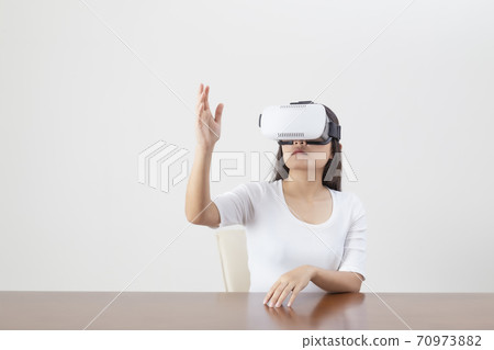 Young woman acting while wearing VR device or virtual reality glasses over white background. 70973882