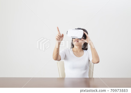 Young woman acting while wearing VR device or virtual reality glasses over white background. Young woman acting while wearing VR device or virtual reality glasses over white background. 70973883