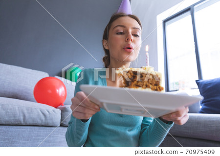 Woman blowing candle on cake at home 70975409