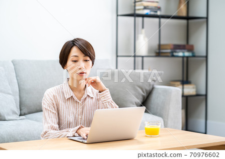 一名中年婦女在客廳里遠程辦公。 一名中年婦女在客廳里遠程辦公。 70976602