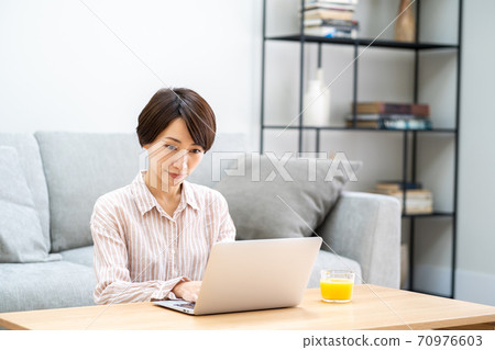 一名中年婦女在客廳里遠程辦公。 一名中年婦女在客廳里遠程辦公。 70976603