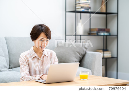 一名中年婦女在客廳里遠程辦公。 一名中年婦女在客廳里遠程辦公。 70976604