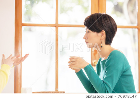 A woman talking with a friend at a cafe 70978147
