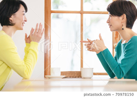 A woman talking with a friend at a cafe A woman talking with a friend at a cafe 70978150