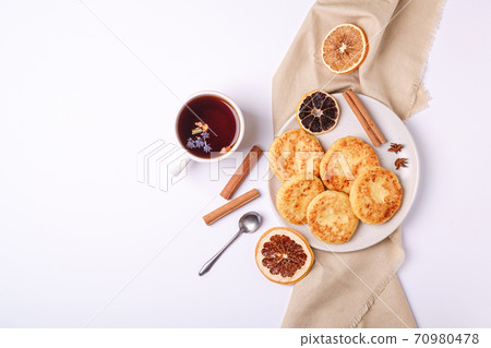 Cottage cheese fritters with hot black aromatic tea, Christmas breakfast mood with anise and cinnamon on white background, top view Cottage cheese fritters with hot black aromatic tea, Christmas breakfast mood with anise and cinnamon on white background, top view 70980478
