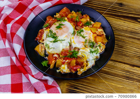 Homemade breakfast shakshuka - fried eggs, onion, bell pepper, tomatoes and dill on rustic wooden table. Jewish cuisine 70980866