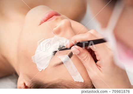 Woman receiving eyelash extensions procedure Woman receiving eyelash extensions procedure 70981876