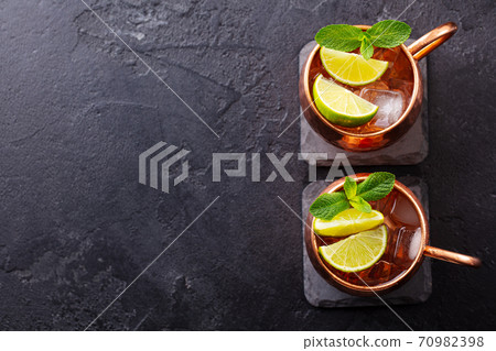 Moscow Mules cocktail with ginger beer, vodka, lime and mint. Grey background. Copy space. Top view. 70982398