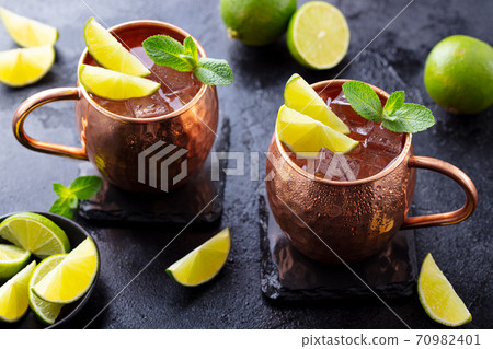 Moscow Mules cocktail with ginger beer, vodka, lime and mint. Grey background. Close up. 70982401