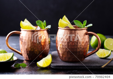 Moscow Mules cocktail with ginger beer, vodka, lime and mint. Grey background. Close up. 70982404