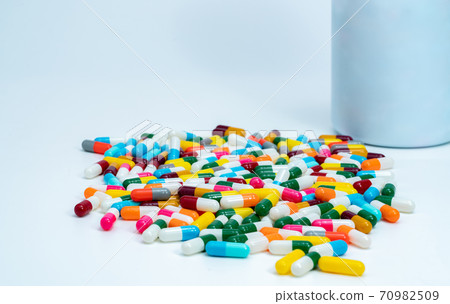 Colorful capsule pills near plastic drug bottle. Multi-colored capsule pills on white table. Pharmacy drugstore products. Pharmaceutical industry. Health budget and policy. Bright colors capsule pills Colorful capsule pills near plastic drug bottle. Multi-colored capsule pills on white table. Pharmacy drugstore products. Pharmaceutical industry. Health budget and policy. Bright colors capsule pills 70982509