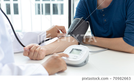 Female doctors use blood pressure monitors and stethoscope to measure pulse Diagnose the patient's disease in a modern hospital medical laboratory, Medical treatment and health care concept. Female doctors use blood pressure monitors and stethoscope to measure pulse Diagnose the patient's disease in a modern hospital medical laboratory, Medical treatment and health care concept. 70982663