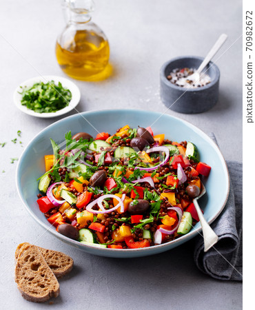 Lentil salad with mix vegetables in bowl. Grey background. Lentil salad with mix vegetables in bowl. Grey background. 70982672