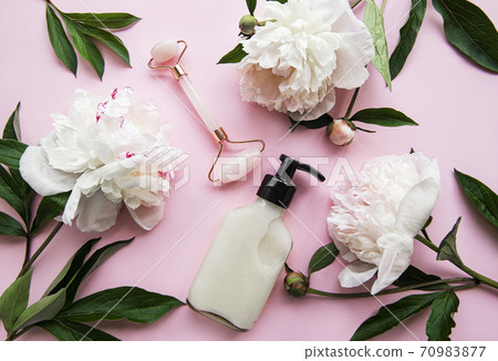 Jade face roller for beauty facial massage therapy, massage oils and pink peonies. 70983877