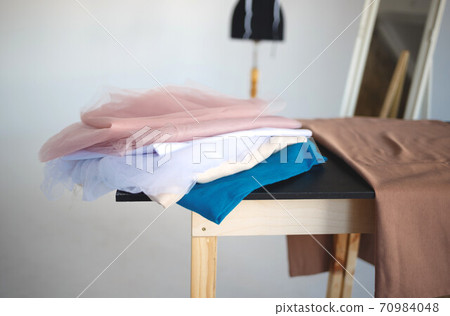a stack of fabrics and sewing accessories on a tailor's table a stack of fabrics and sewing accessories on a tailor's table 70984048