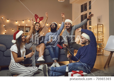 Cheerful young friends drinking champagne and wishing each other Merry Xmas and Happy New Year Cheerful young friends drinking champagne and wishing each other Merry Xmas and Happy New Year 70985365